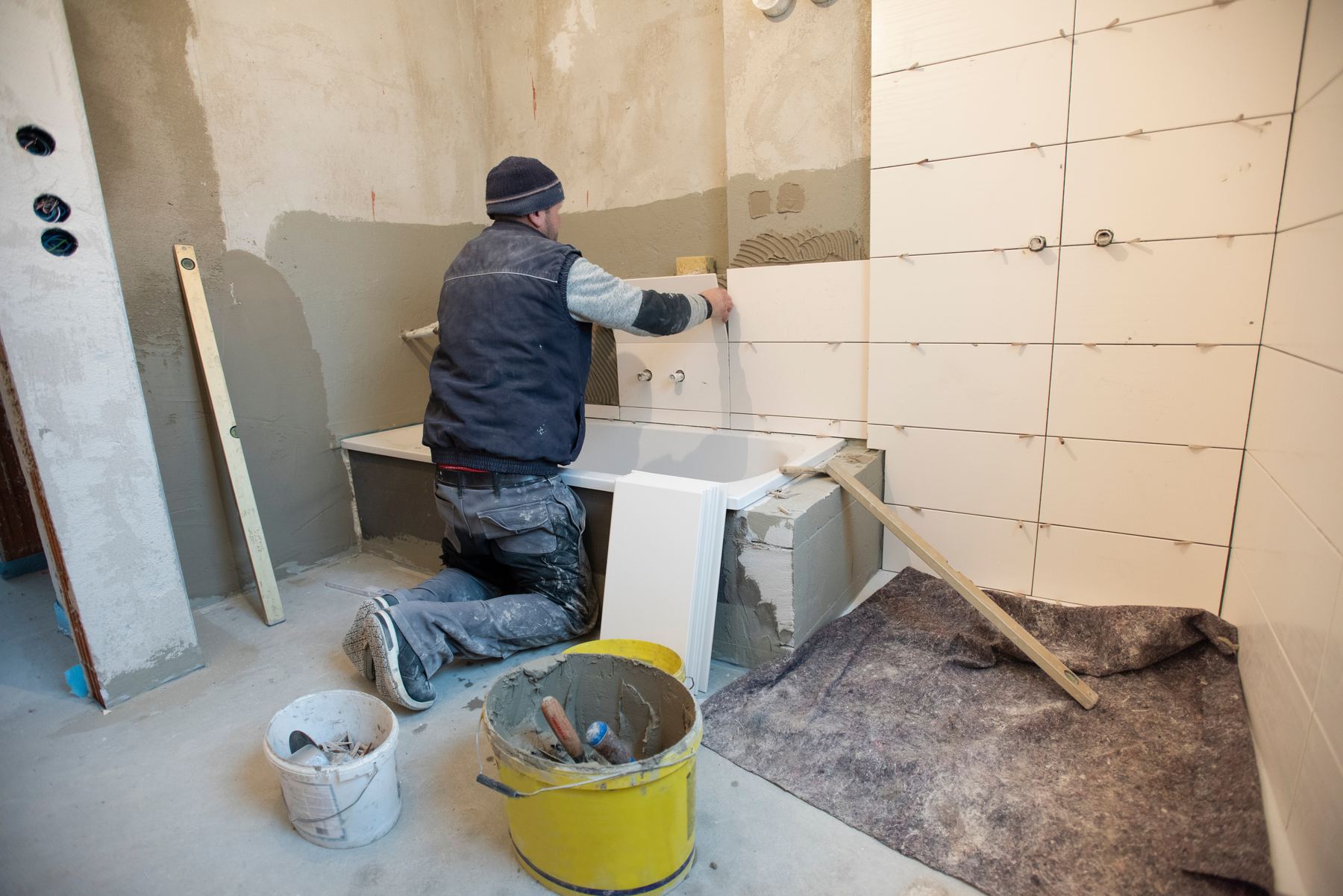Handwerker verlegt Fliesen im Innenausbau