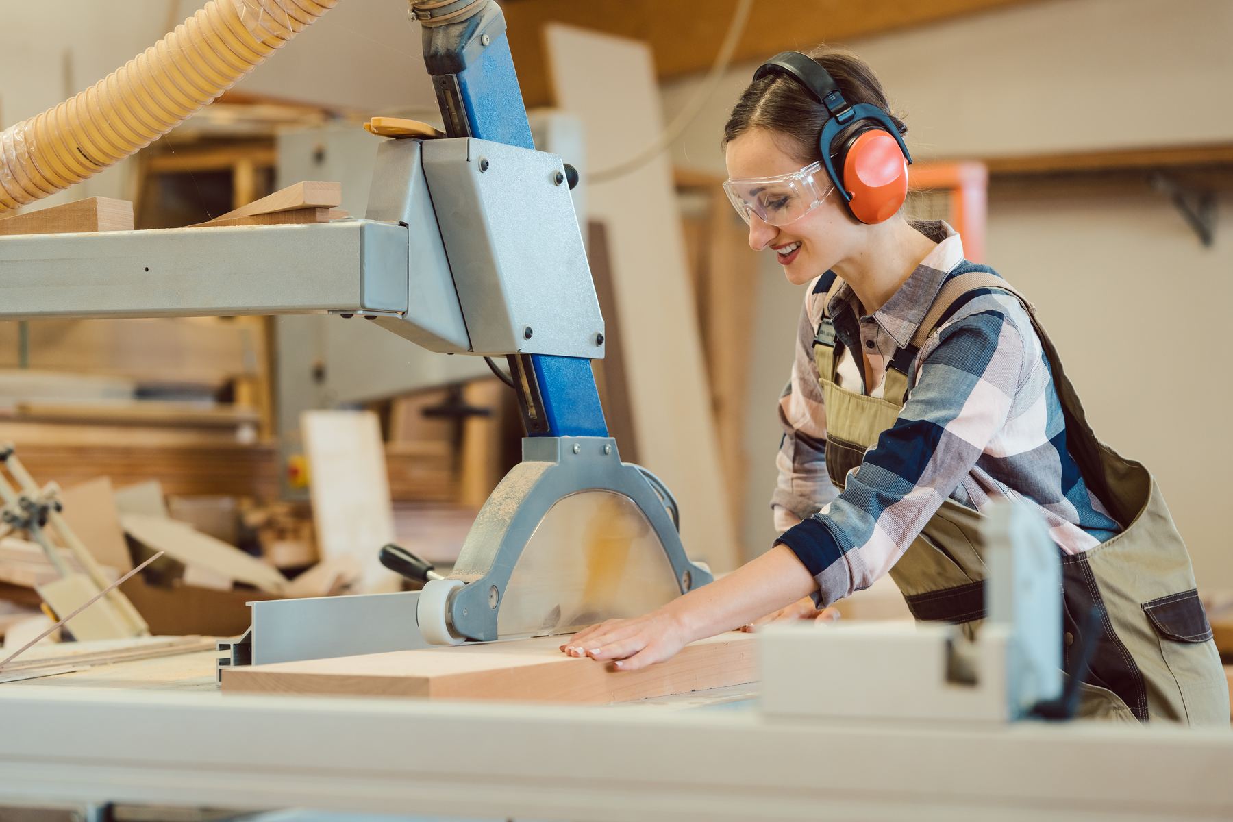 Handwerkerin arbeitet an der Tischkreissäge in der Werkstatt